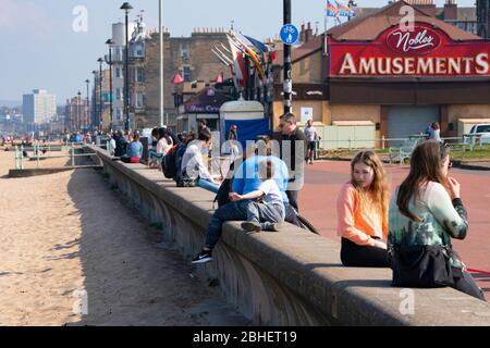 Portobello, Schottland, Großbritannien. 25. April 2020. Blick auf die Menschen im Freien am Samstagnachmittag am Strand und an der Promenade in Portobello, Edinburgh. Gutes Wetter hat mehr Menschen ins Freie gebracht, die wandern und Radfahren. Der Strand scheint voll mit möglicherweise einem Zusammenbruch der sozialen Distanz, die später am Nachmittag stattfindet. Die Ufermauer ist voll mit Leuten, die draußen sitzen. Iain Masterton/Alamy Live News Stockfoto