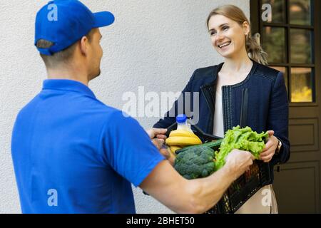 Frau erhalten Online-Lebensmittelbestellbox von Lieferung Mann zu Hause Stockfoto