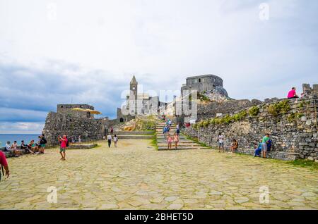 Portovenere, Italien, 13. September 2018: Menschen Touristen in der Nähe der Chiesa San Pietro katholische Kirche, Lord Byron Parque Naturpark in alten mittelalterlichen Stadt, blauer Himmel Hintergrund, La Spezia, Ligurien Stockfoto