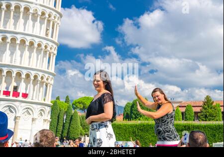 Pisa, Italien, 14. September 2018: Touristen Reisenden kaukasischen und asiatischen Menschen posieren, Spaß haben, stereotype Fotos machen, ein Selfie, so tun, berühmten Schiefen Turm, Toskana zu halten Stockfoto