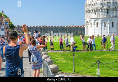 Pisa, Italien, 14. September 2018: Touristen Reisenden kaukasischen und asiatischen Menschen posieren, Spaß haben, stereotype Fotos machen, ein Selfie, so tun, berühmten Schiefen Turm, Toskana zu halten Stockfoto