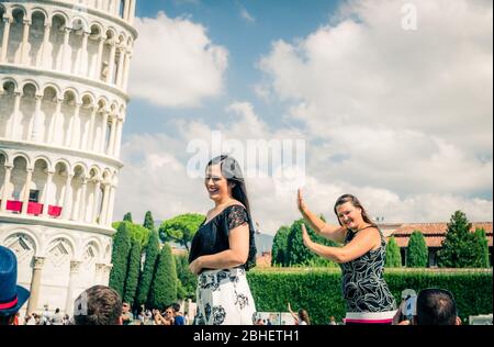 Pisa, Italien, 14. September 2018: Touristen Reisenden kaukasischen und asiatischen Menschen posieren, Spaß haben, stereotype Fotos machen, ein Selfie, so tun, berühmten Schiefen Turm, Toskana zu halten Stockfoto