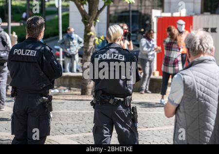 25. April 2020, Hessen, Frankfurt/Main: Polizisten beobachten Demonstranten vor der Alten Oper auf dem Gelände eines Luxushotels. Zum Thema "Flüchtlinge und Wohnungsnot in der Corona-Krise" fanden Aktionen vor zwei Hotels und vor einer Jugendherberge statt. Foto: Frank Rumpenhorst/dpa Stockfoto