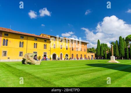 Pisa, Italien, 14. September 2018: Palazzo dell'Opera Palast, Angelo Caduto Statue, Lupa capitolina Denkmal auf Platz mit grünem Rasen, blauer Himmel weiße Wolken Hintergrund bei sonnigen Tag, Toskana Stockfoto