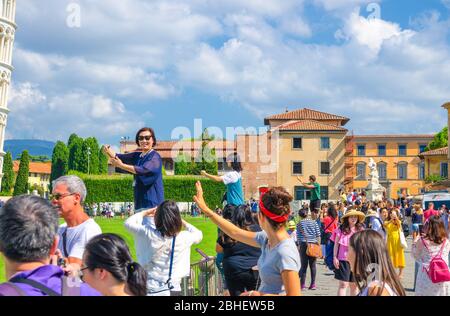 Pisa, Italien, 14. September 2018: Touristen Reisenden kaukasischen und asiatischen Menschen posieren, Spaß haben, stereotype Fotos machen, ein Selfie, so tun, berühmten Schiefen Turm, Toskana zu halten Stockfoto