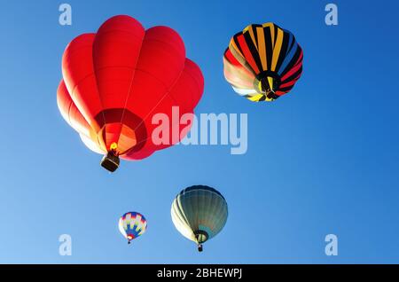 Heißluftballons fliegen im blauen klaren Himmel kurz nach dem Start Stockfoto