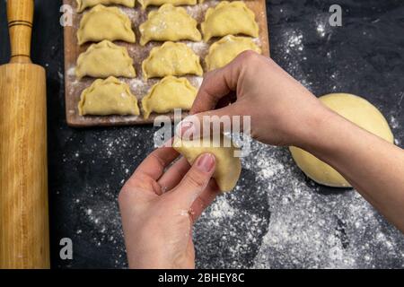 Knödel in Mehl auf dem Holzbrett, die Hände sind varenik vor dem Kochen gemeißelt. Draufsicht, Nahaufnahme Stockfoto