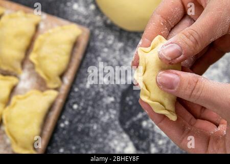 Knödel in Mehl auf dem Holzbrett, die Hände sind varenik vor dem Kochen gemeißelt. Draufsicht, Nahaufnahme Stockfoto