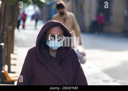 Barcelona, Spanien. April 2020. Ältere Frau, die auf den Straßen von Barcelona spazieren geht und eine schützende Gesichtsmaske und trendige Sonnenbrille trägt Stockfoto