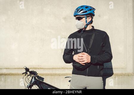 Portrait Radsportler in der Nähe von grauen Betonwand in Schutzmaske PM 2.5 mit Filter. Schützen Sie die menschlichen Atemorgane vor Staub und Schwebung Stockfoto