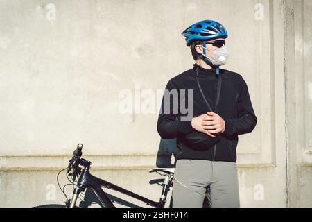 Portrait Radsportler in der Nähe von grauen Betonwand in Schutzmaske PM 2.5 mit Filter. Schützen Sie die menschlichen Atemorgane vor Staub und Schwebung Stockfoto