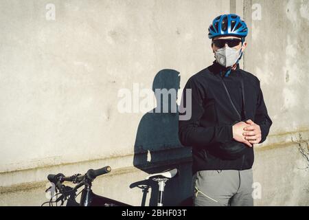 Portrait Radsportler in der Nähe von grauen Betonwand in Schutzmaske PM 2.5 mit Filter. Schützen Sie die menschlichen Atemorgane vor Staub und Schwebung Stockfoto