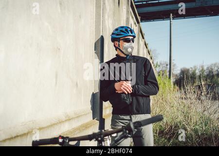 Portrait Radsportler in der Nähe von grauen Betonwand in Schutzmaske PM 2.5 mit Filter. Schützen Sie die menschlichen Atemorgane vor Staub und Schwebung Stockfoto