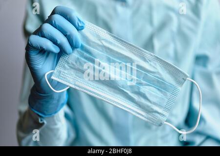 Ein Arzt in medizinischen Handschuhen dosiert eine gebrauchte Gesichtsmaske. Nahaufnahme. Stockfoto