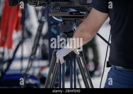 Details mit der Hand in Handschuhen eines Videobedieners während der covid-19-Sperre. Coronavirus und das Pressekonzept. Stockfoto
