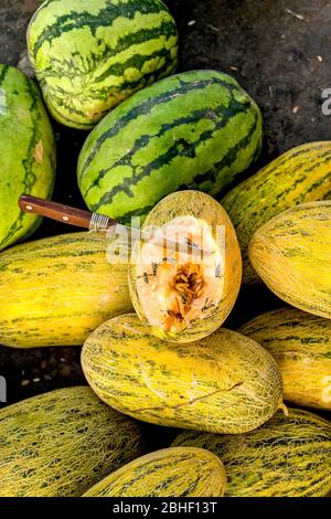 Hami Melone geöffnet, bereit für die Verkostung. Zieht viele Bienen und andere Insekten an. Auf dem alten Basar (Markt) in Kuqa, Xinjiang, Westchina Stockfoto