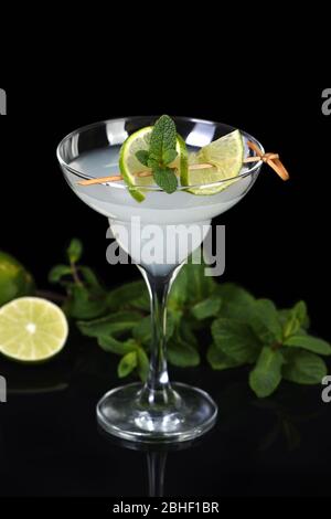 Tequila, Zitruslikör, Limettensaft - das ist ein Margarita-Cocktail. Ein Kalkstein mit einem Zweig Minze schmückt ein Glas. Dunkles, launisch gelauntes Essen Stockfoto