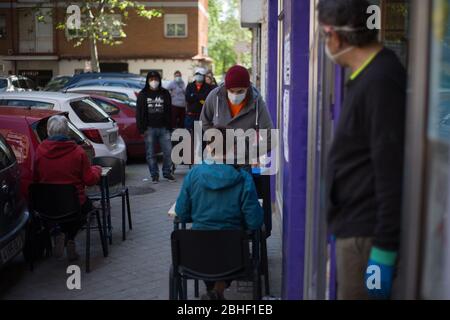 Madrid, Spanien. 25. Apr 2020. Mehrere Leute warten auf ihre Zuzug, um Nahrung zu erhalten. (Foto von Fer Capdepon Arroyo/Pacific Press) Quelle: Pacific Press Agency/Alamy Live News Stockfoto