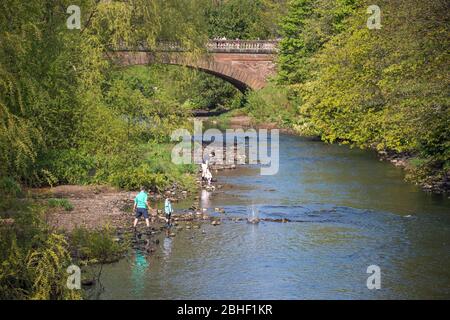 Glasgow, Großbritannien. April 2020. Im Bild: Menschen, die im Wasser des Flusses Kelvin spielen, der durch den Rand des Kelvingrove Parks schlängelt. Szenen vom ersten Wochenende der erweiterten Sperrung des Kelvingrove Park im West End von Glasgow an einem sehr heißen und sonnigen Samstag. Quelle: Colin Fisher/Alamy Live News Stockfoto