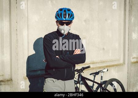 Portrait Radsportler in der Nähe von grauen Betonwand in Schutzmaske PM 2.5 mit Filter. Schützen Sie die menschlichen Atemorgane vor Staub und Schwebung Stockfoto