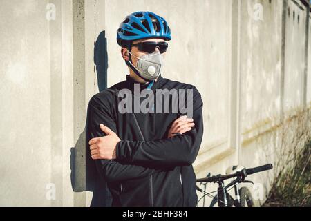 Portrait Radsportler in der Nähe von grauen Betonwand in Schutzmaske PM 2.5 mit Filter. Schützen Sie die menschlichen Atemorgane vor Staub und Schwebung Stockfoto