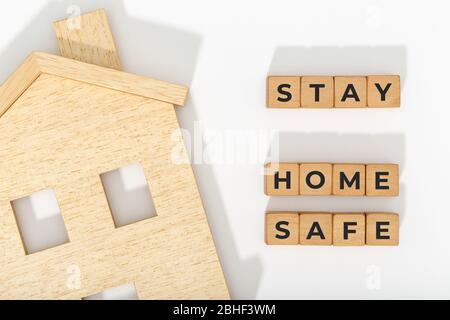 Zu Hause bleiben Bleib sicher Konzept. Coronavirus COVID-19 Ausbruchsempfehlung. Home-Symbol und Holzblöcke auf weißem Hintergrund Stockfoto