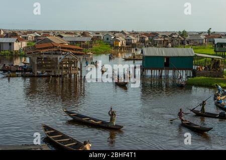 Ganvie Dorf Übersicht mit Menschen, die mit dem Boot herumkommen. Das Dorf ist ein einzigartiges Dorf auf Stelzen gebaut, am See Nokoue in der Nähe von Cotonou, Benin. Stockfoto