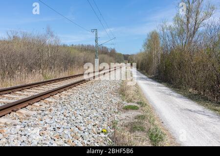 Gerader Blick auf einen Fußweg und Bahngleise. Die Gleise sind Teil des öffentlichen Verkehrsnetzes München. Konzept für Reisen, Reisen, weite Wege. Stockfoto