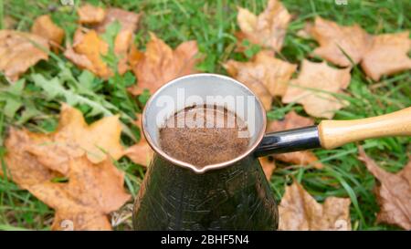 Kaffee in einer türkischen Kanne brauen - im Freien über die Herbstblätter Stockfoto