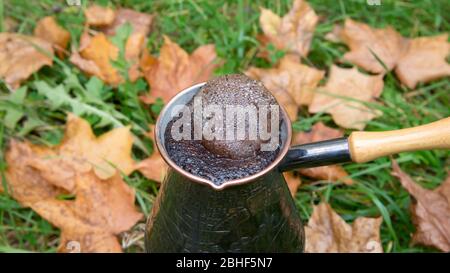 Kaffee in einer türkischen Kanne brauen - im Freien über die Herbstblätter Stockfoto