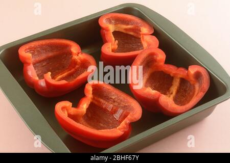 Frische rohe rote Paprika halbiert in Antihaft-Backform zum Kochen vor dem Stopfen Stockfoto