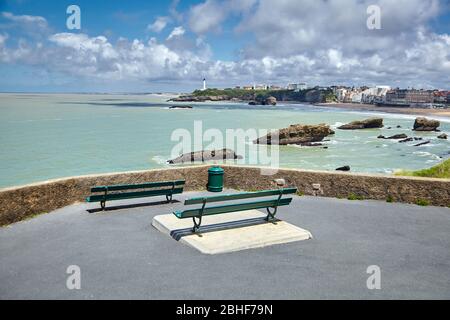 Leere Holzbänke auf einem Park mit Blick auf das Meer und den Leuchtturm. Das Hotel liegt in Biarritz, Frankreich Stockfoto