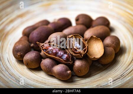 Getrocknete Bio-exotische Tamarindenfrüchte in Bambus Schüssel Nahaufnahme. Makroaufnahmen in Studio Stockfoto