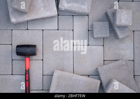 Pflastersteine Pflastersteine Hintergrund. Werkzeug Gummihammer auf Vordergrundfarbe montieren Stockfoto