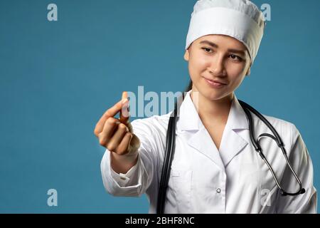 Junge Ärztin, die eine Pille hält, sie anschaut und sie als Behandlung für den Patienten gibt Stockfoto