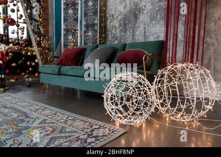 Weihnachten glühende Girlande in Form von Kugeln. Wunderschöne Lampen. Bunte Lichter, grünes Sofa im Wohnzimmer. Einrichtung mit Glühbirnen. Moderne weihnachten Stockfoto