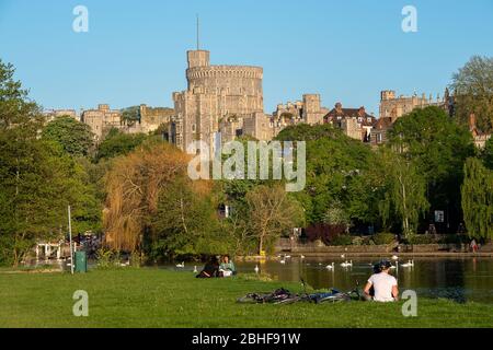 Eton, Windsor, Berkshire, Großbritannien. April 2020. Die Menschen sitzen an der Themse auf dem Brocas in Eton mit Blick auf Windsor Castle. Nach Regierungsrat Menschen in England erlaubt, tägliche Übung einmal täglich während der Coronavirus Pandemie zu nehmen. Sie dürfen sich während des Trainings ausruhen, aber nur kurz. Kredit: Maureen McLean/Alamy Live News Stockfoto