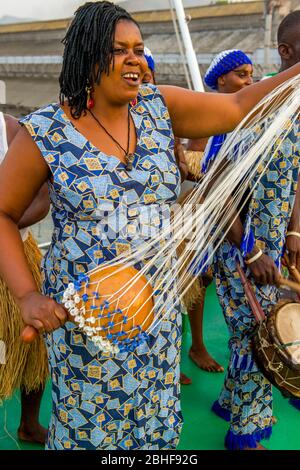 Performance der National Dance Troupe of Sierra Leone an Bord der MS Expedition im Hafen von Freetown mit einer Frau, die Shekere gourd instrumentiert Stockfoto