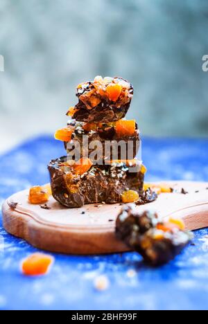 In Scheiben geschnittene Schokolade mit getrockneten Aprikosen, Rosinen, Leinsamen, Sesam ​​homemade. Auf blauem Hintergrund. Stockfoto