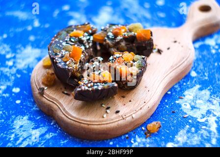 In Scheiben geschnittene Schokolade mit getrockneten Aprikosen, Rosinen, Leinsamen, Sesam ​​homemade. Auf blauem Hintergrund. Stockfoto