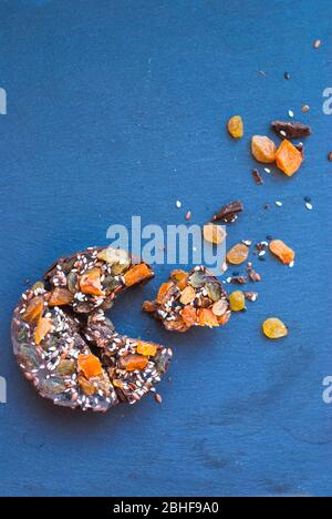 In Scheiben geschnittene Schokolade mit getrockneten Aprikosen, Rosinen, Leinsamen, Sesam ​​homemade. Auf blauem Hintergrund. Stockfoto