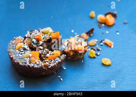 In Scheiben geschnittene Schokolade mit getrockneten Aprikosen, Rosinen, Leinsamen, Sesam ​​homemade. Auf blauem Hintergrund. Stockfoto