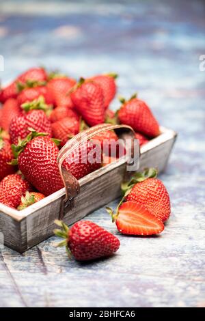 Viele frische, rote Erdbeeren in einem Holzkorb auf blauweißem Hintergrund Stockfoto