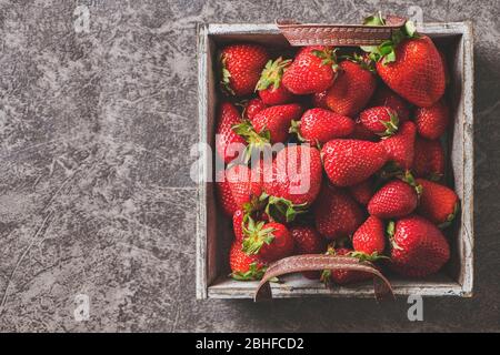 Erdbeeren in einem Holzkorb auf dunkelgrauem Hintergrund Stockfoto