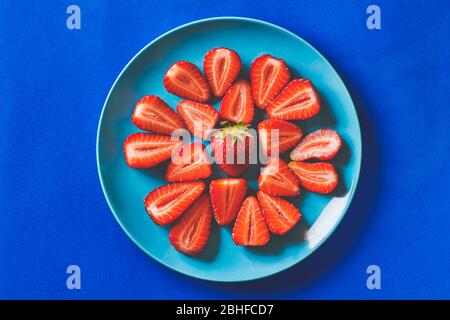 Frische Erdbeeren in einem blauen Teller auf einem dunkelblauen Karton Hintergrund Stockfoto