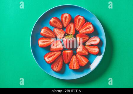 Frische Erdbeeren in einem blauen Teller auf einer grünen Pappe Stockfoto