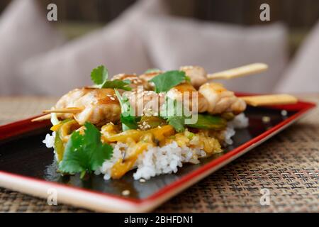 Yakitori-Huhn mit Reis und Koriander auf dem Tisch des Restaurants Stockfoto