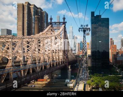 Midtown Manhattan und Ed Koch Queensboro Bridge von Roosevelt Tramway mit sichtbaren Kabeln. Sonniger Tag, blauer Himmel mit ein paar Wolken. Keine Personen sichtbar. Stockfoto