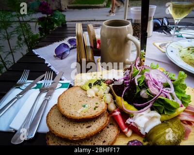 Österreichische Brotzeit Platte mit großer Auswahl an Gemüse und Würstchen mit Bier. Tageslichtaufnahme eines typisch bayerischen Vorspeisenspeisevorspeisers. Stockfoto