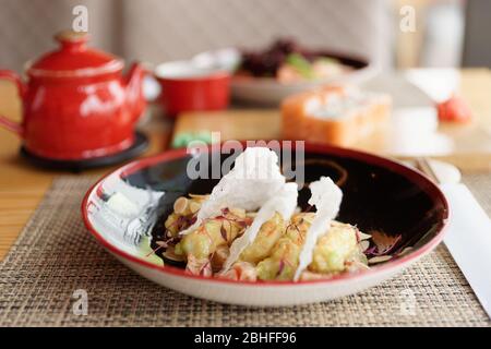 Gebratene Garnelen in Wasabi-Sauce auf dem Restauranttisch, asiatische Speisen Stockfoto
